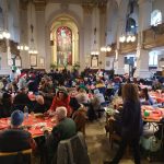 St Philips Cathedral Birmingham filled with festively decorated round tables laden down with Christmas feast being enjoyed by the people that Let's Feed Brum supports.